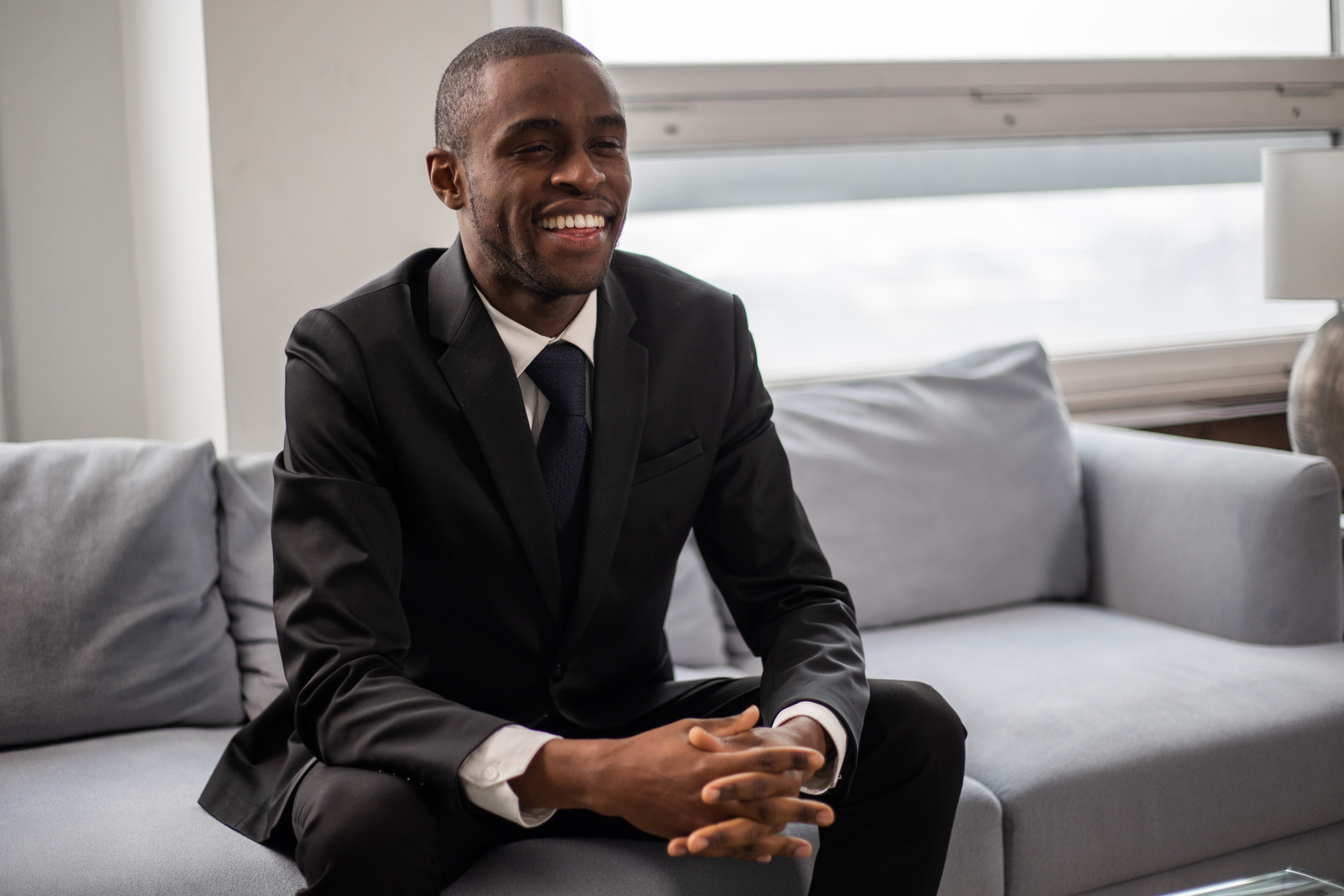 Happy Man in Black Suit Sitting on a Couch